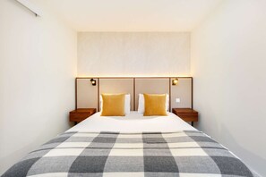Ein Hotelzimmer mit einem großen Bett, zwei Nachttischen und einem Kopfteil mit integrierter Beleuchtung.