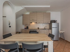 A compact kitchen with wooden cabinets, a built-in microwave, and a refrigerator. - Stefani by Interhome (Lago di Ledro)