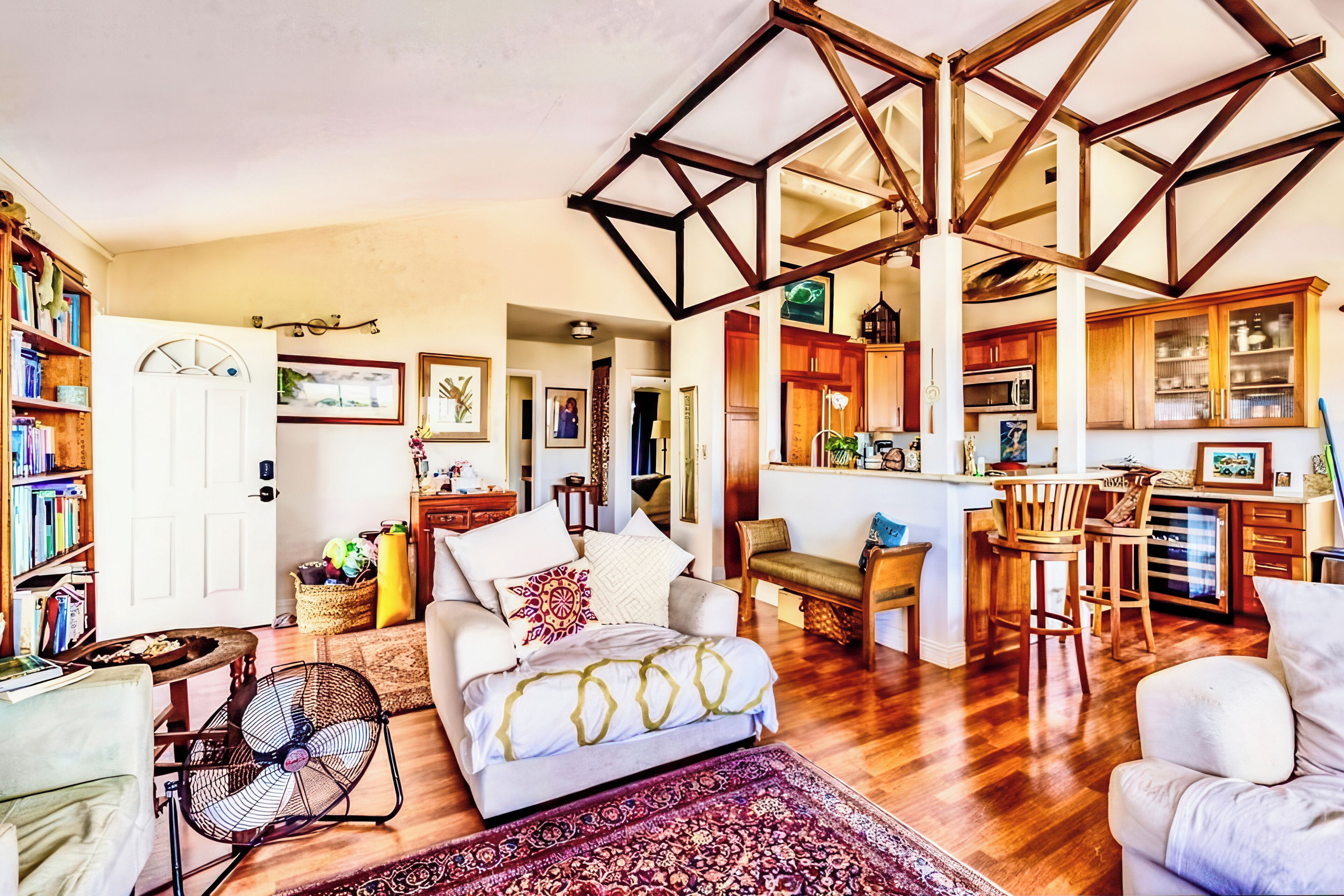 A spacious living area with a large bed, a dining table, and a kitchen in the background.