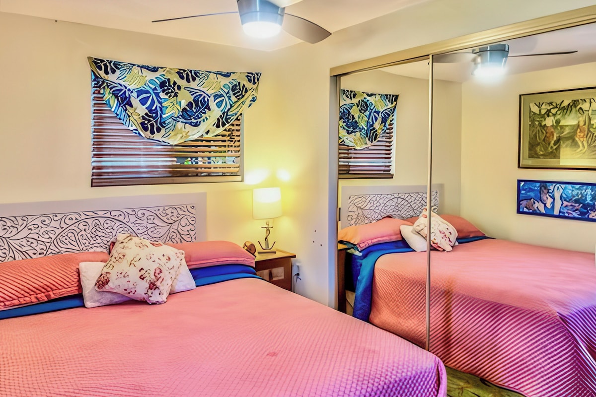 A hotel room with two beds, a large mirror, and artwork on the walls.