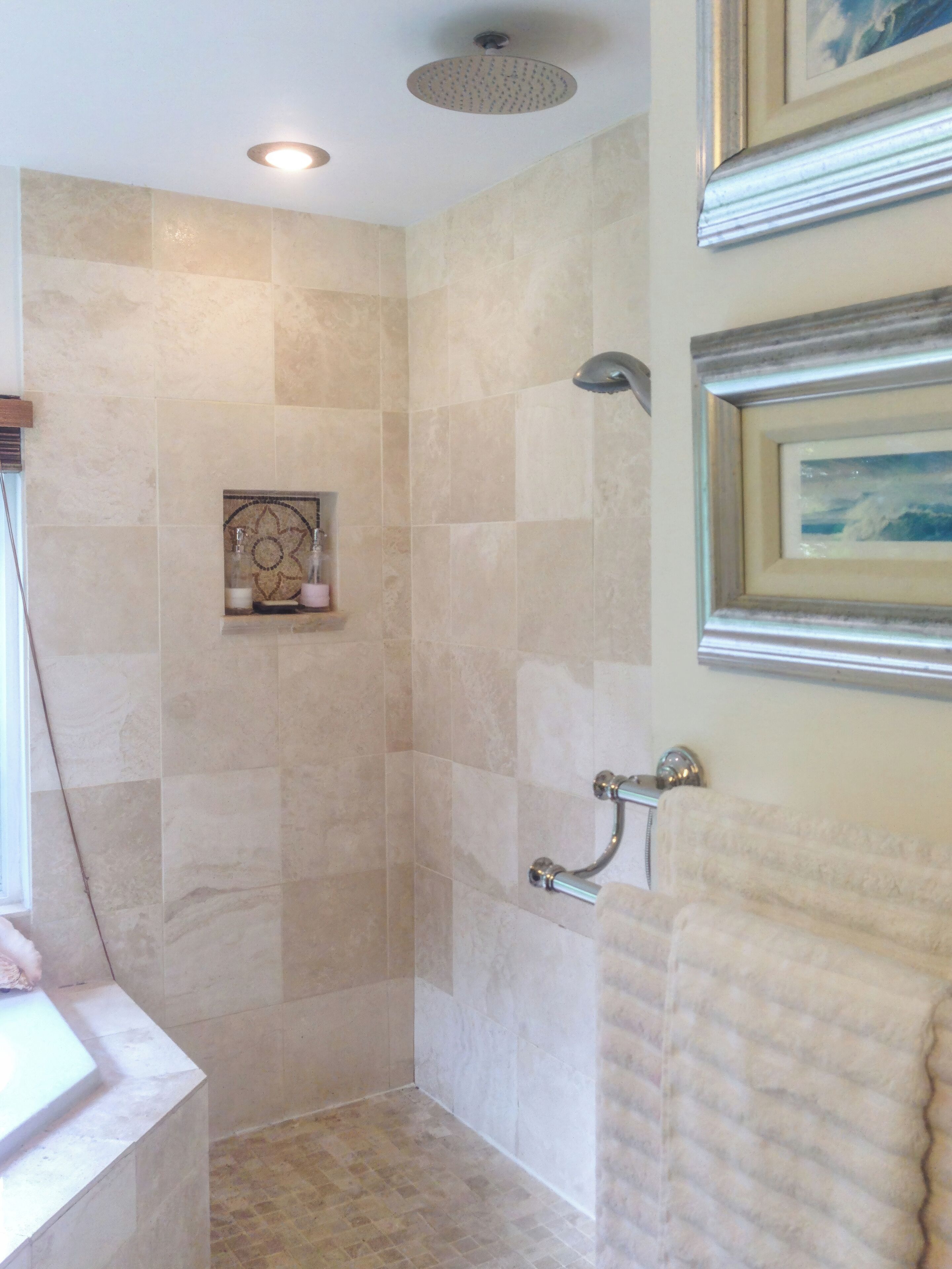 A bathroom with a shower, tiled walls, a framed picture, and a towel rack.