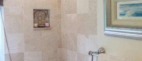 A bathroom with a shower, tiled walls, a framed picture, and a towel rack.