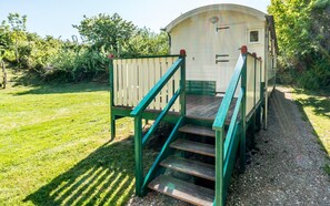 A small, single-story structure with a wooden deck and a staircase leading to a door. - Camper Foundation Sophie (Burgh-Haamstede)