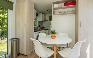 A compact kitchen with a dining area, a washing machine, and a potted plant. - Camper Foundation Sophie (Burgh-Haamstede)
