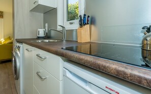 Eine Küche mit Spüle aus Edelstahl, einem Wasserkocher und einem Messerblock.