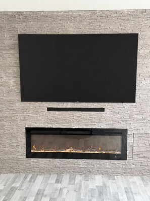 Ein moderner Kamin mit einem flachbildfernseher darüber.