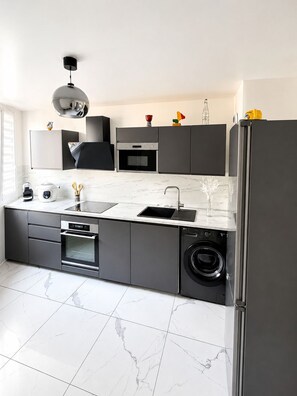 A modern kitchen with a built-in oven, microwave, and dishwasher. - A beautiful, chic, and cozy home near Paris. (Créteil)