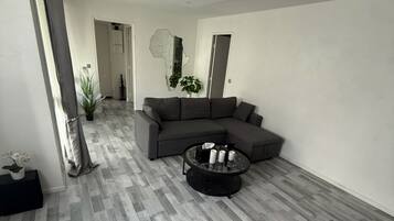 Een moderne woonkamer met een hoekbank, een ronde salontafel en een groot raam.