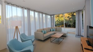 Ein modernes Wohnzimmer mit einem Ecksofa, zwei Sesseln, einem Couchtisch und einem Fernseher.