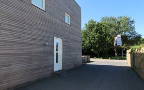 Un bâtiment à la façade plate, doté d’une porte, d’un chemin pavé et d’une enseigne.