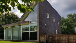Ein modernes, zweistöckiges Haus mit großen Fenstern und einem Holzzaun.