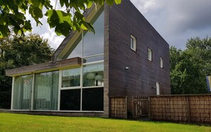 Ein modernes, zweistöckiges Haus mit großen Fenstern und einem Holzzaun.