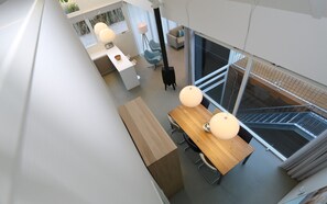 A modern interior with a dining area featuring a wooden table and chairs, pendant lights, and a view of a staircase. - Horizon 99 comfortable villa for a majestic vacation (Renesse)