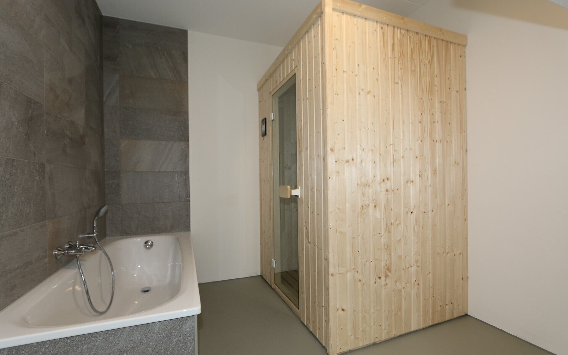Baño con bañera, puerta de madera y pared con azulejos.
