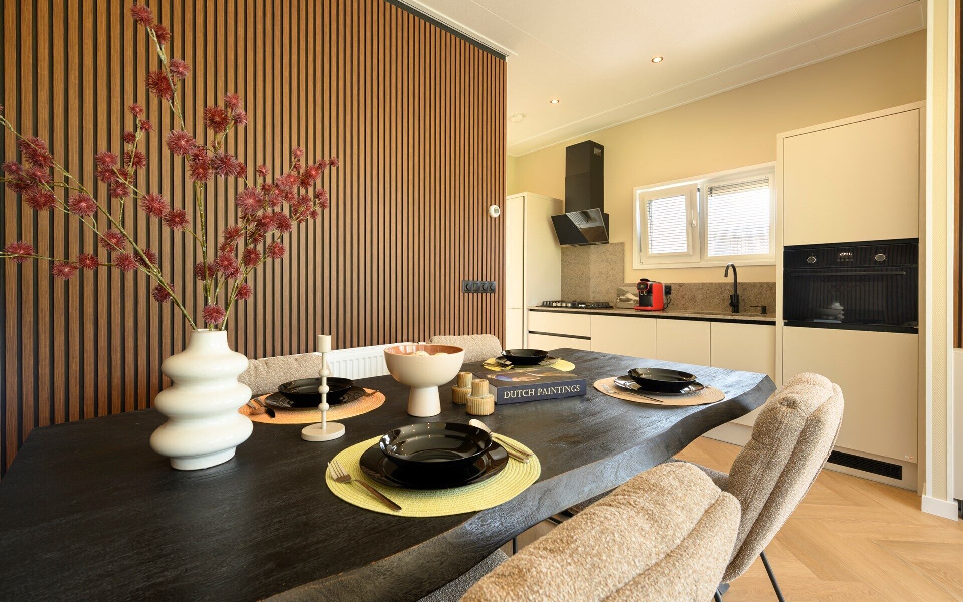 Een moderne eetruimte met een donker houten tafel, witte stoelen en een vaas met rode bloemen.