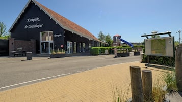 A reception building with a sign reading 'Kustpark de Strandlooper' and a playground with a slide in the background.