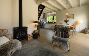 A cozy living room with a fireplace, a dining area, and a kitchen in the background. - Zeeduin "Neeltje" detached holiday home with large private garden (Burgh-Haamstede)