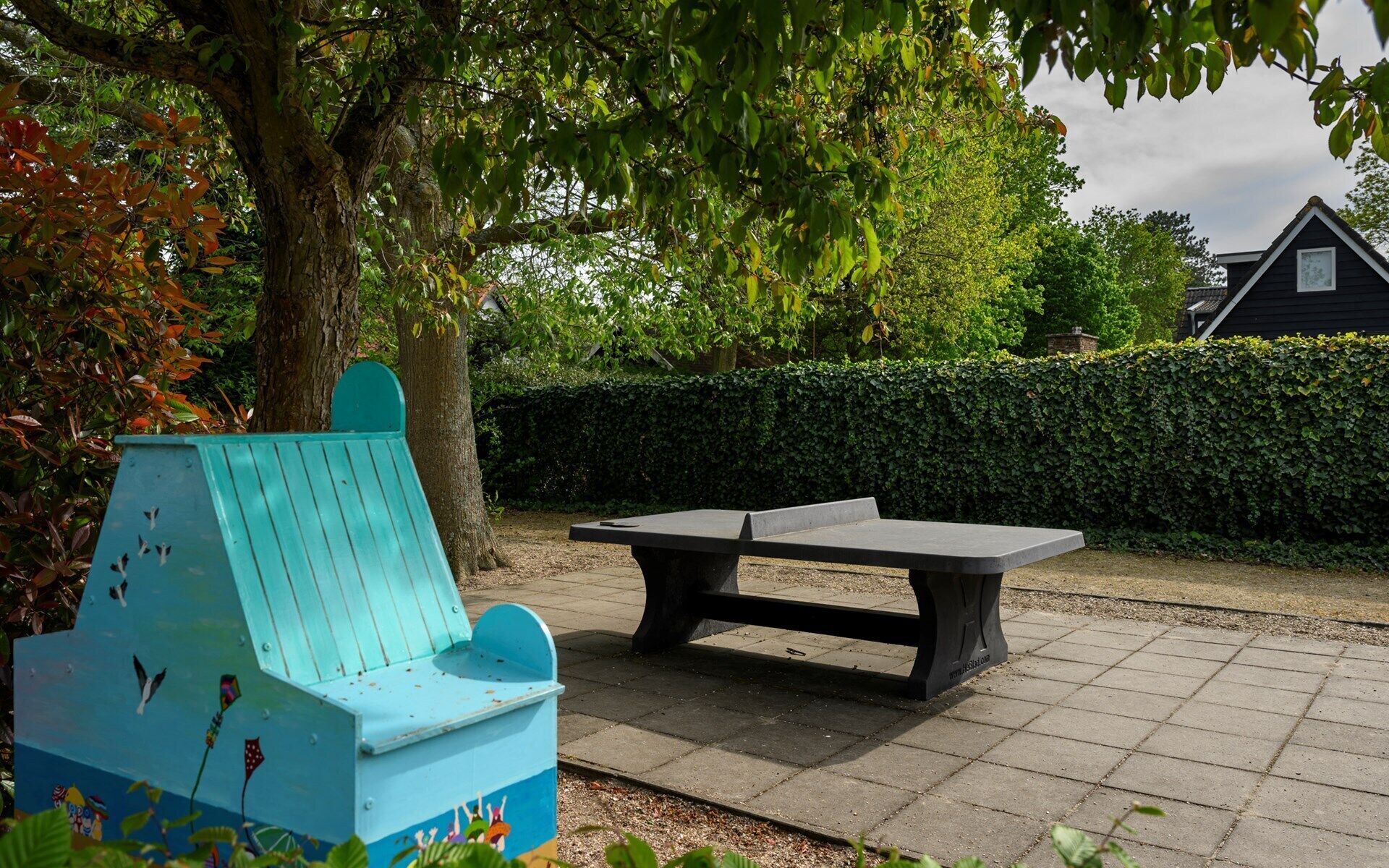Een bankje en een vogelhuisje in een park.