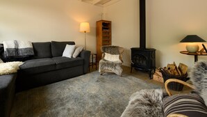 Una sala de estar acogedora con un sofá, una silla, una chimenea y una lámpara.