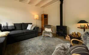 Ein gemütliches Wohnzimmer mit Sofa, Sessel, Kamin und Lampe.