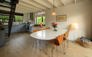Eine moderne Küche mit Essbereich, Holzboden und Blick auf Grünflächen.