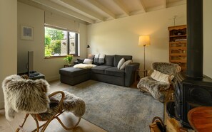 A cozy living room with a sofa, a furry chair, a fireplace, and a bookshelf. - Zeeduin "Neeltje" detached holiday home with large private garden (Burgh-Haamstede)