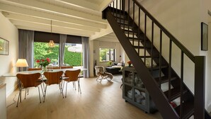 Un salón amplio con una mesa de comedor, sillas y una escalera.