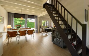 A spacious living area with a dining table, chairs, and a staircase.