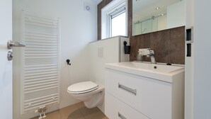 A modern bathroom with a toilet, a sink, and a mirror. - Hoeve Lodge "De Meidoorn" (Burgh-Haamstede)