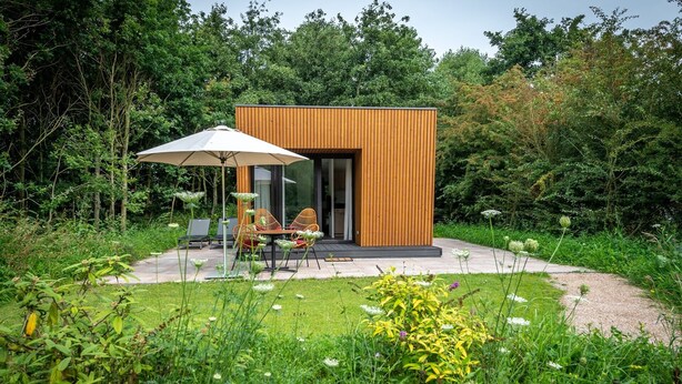 A modern wooden cabin with a patio, outdoor seating, and a garden. - Hoeve Lodge "De Meidoorn" (Burgh-Haamstede)