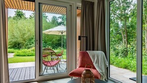 A room with a large sliding glass door leading to an outdoor patio with a table, chairs, and a garden view. - Hoeve Lodge "De Meidoorn" (Burgh-Haamstede)