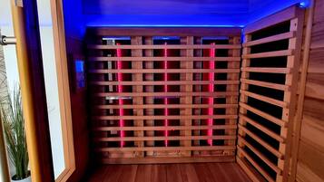 A sauna with a wooden lattice structure and red lighting.