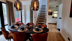 A dining area with a round table, chairs, and hanging pendant lights.