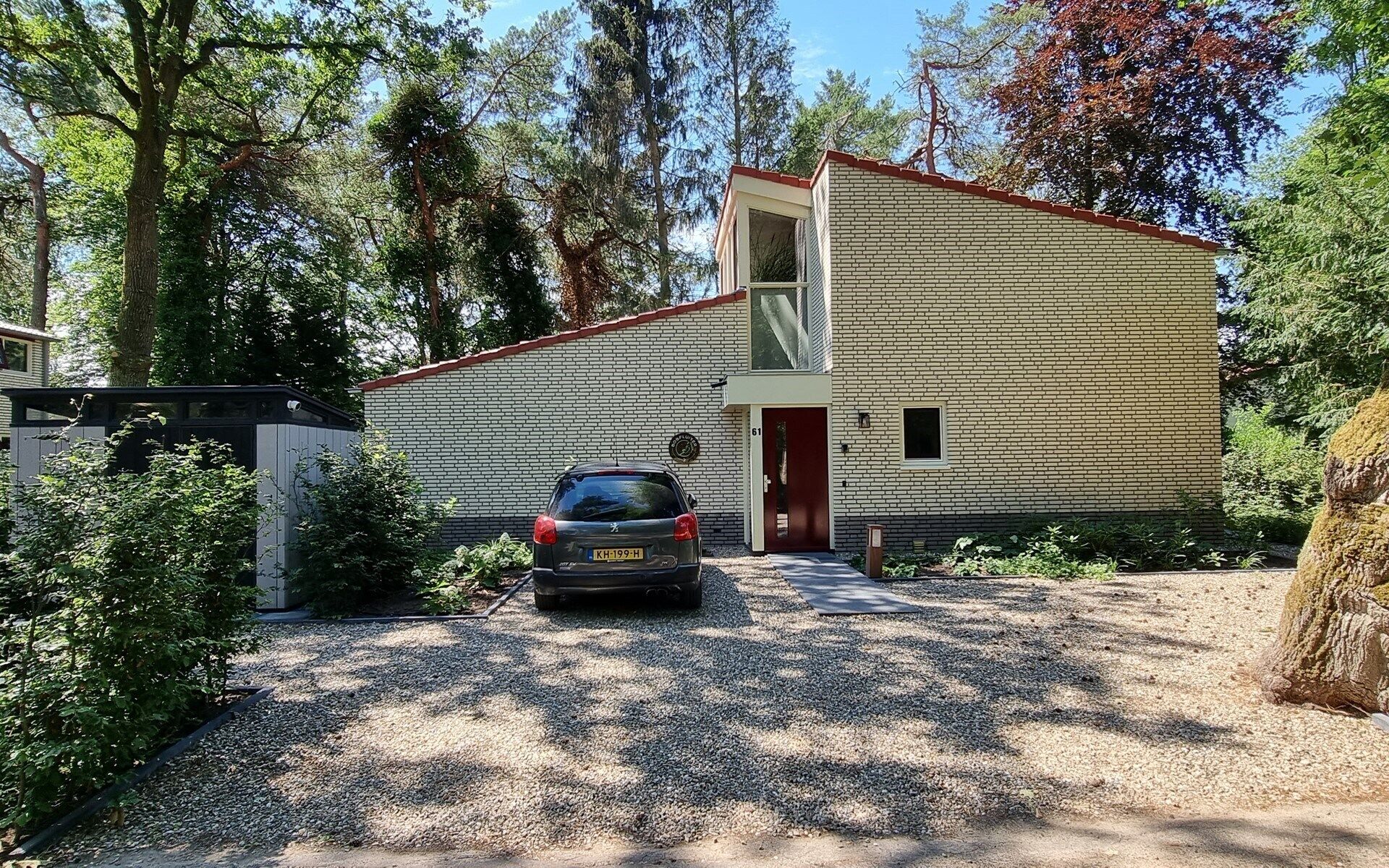 Een gebouw met twee verdiepingen, een gevel van baksteen, een auto ervoor en een grindpad.