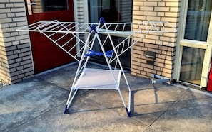A metal laundry basket with blue handles on a concrete surface.