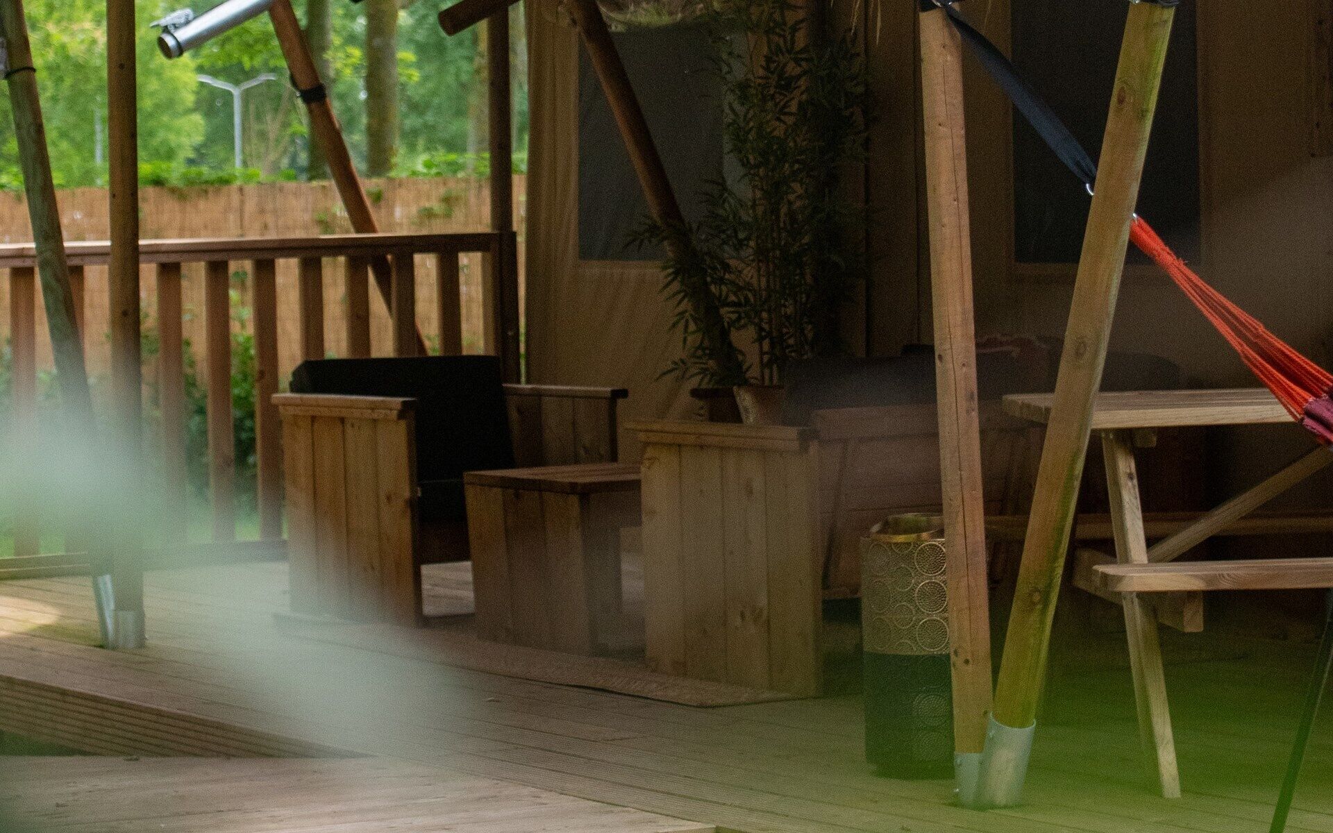 A wooden deck with a telescope, a hammock, and a potted plant.