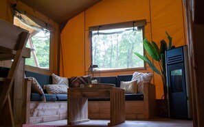 Ein gemütliches Zimmer mit einer hölzernen Bank, Kissen, einem kleinen Tisch und einer großen Pflanze.