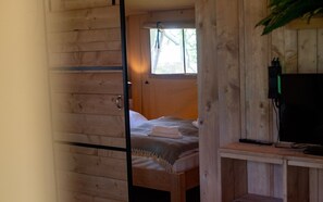 Ein Zimmer aus Holz mit einem Bett, einem Schreibtisch und einem Fenster.