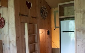 Ein Holzinnenraum mit einer Leiter, einer Tür und einem Kühlschrank.