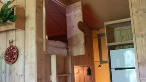 A room with a wooden ceiling, a white refrigerator, and a door with a towel hanging on it. - Luxury Safari Tent Renesse (Renesse)
