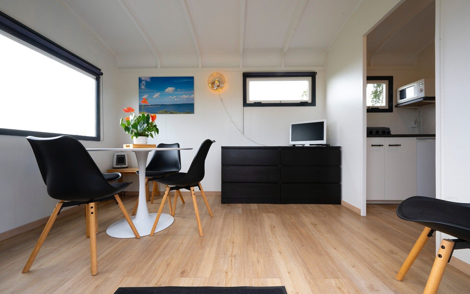 A modern kitchen with a dining area, a flat-screen TV, and a large window.