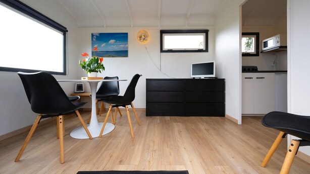 A modern kitchen with a dining area, a flat-screen TV, and a large window.