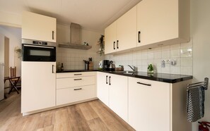 A modern kitchen with white cabinets, a black countertop, and a stainless steel range hood.