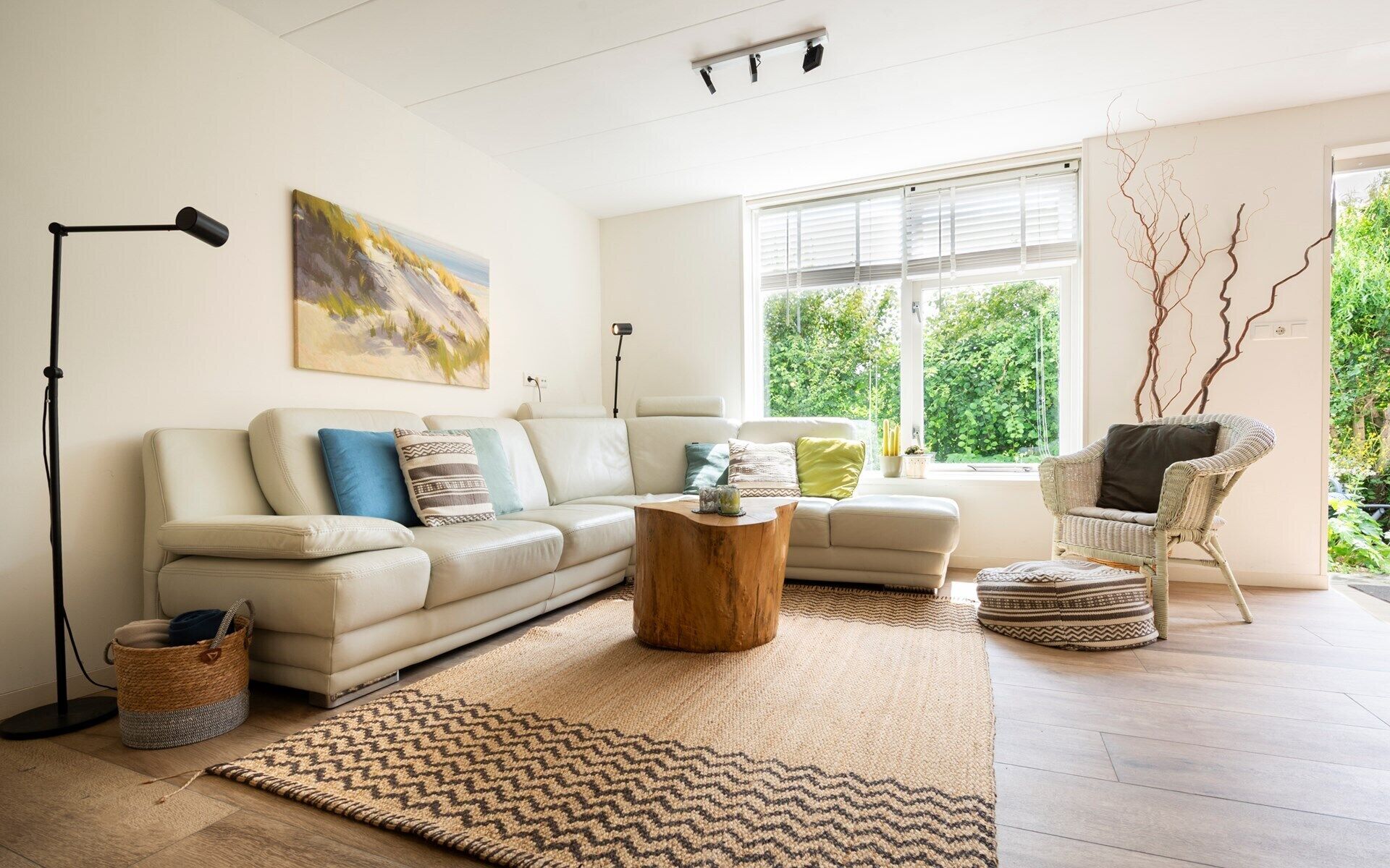 A modern living room with a beige sofa, a wooden coffee table, a floor lamp, and a wicker chair.