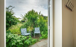 A doorway leading to a garden with two chairs and a metal bench. - Cottage in the Orchard (Burgh-Haamstede)