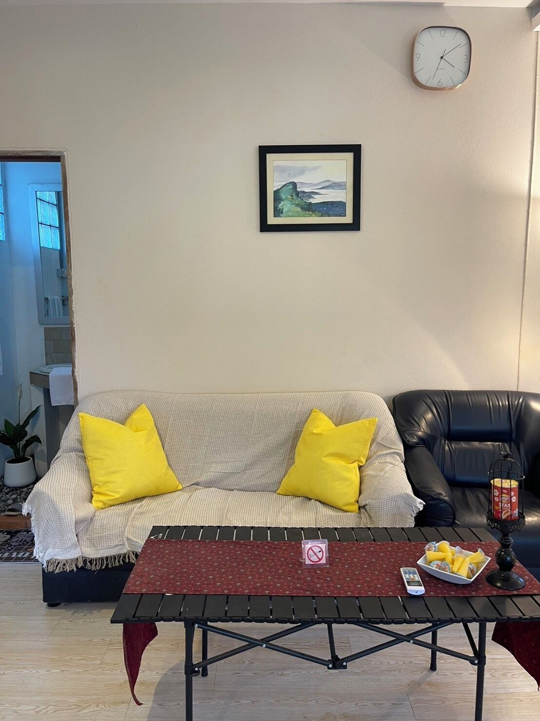 Una sala de estar con un sofá, una mesa de centro, un reloj y un cuadro en la pared.