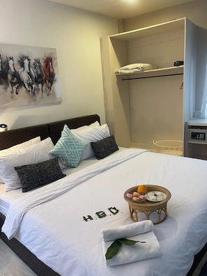 A neatly made bed with a white bedspread, pillows, and a basket of fruit.