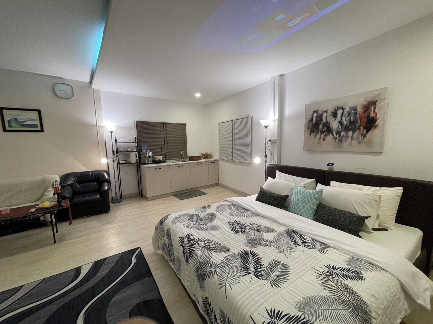 Un dormitorio moderno con una cama grande, un escritorio y una kitchenette.
