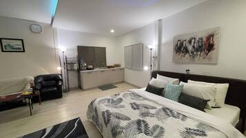 Un dormitorio moderno con una cama grande, un escritorio y una kitchenette.