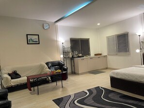 A compact living space with a sofa, a dining table, a kitchenette, and a bed. - Rural Stay Baan Mea Pen  Nature Retreat  (Chiang Rai)